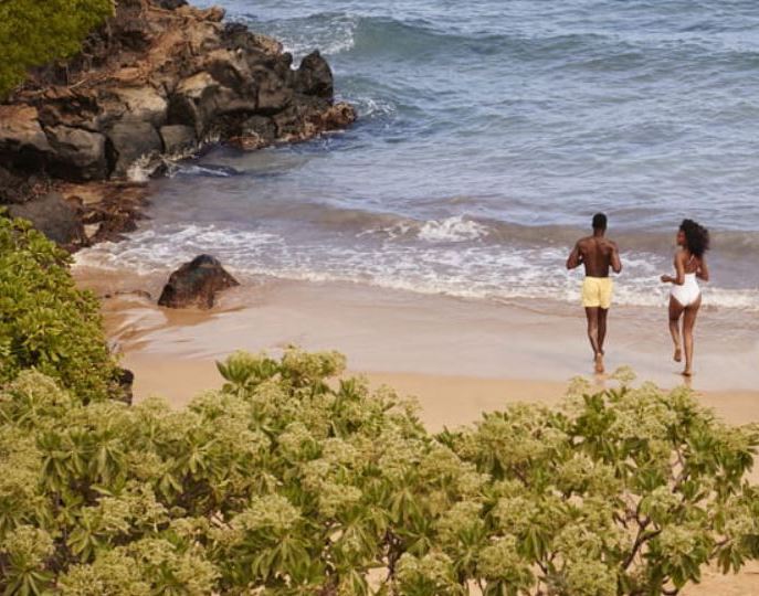 A man and a woman running on the beach during a romantic getaway