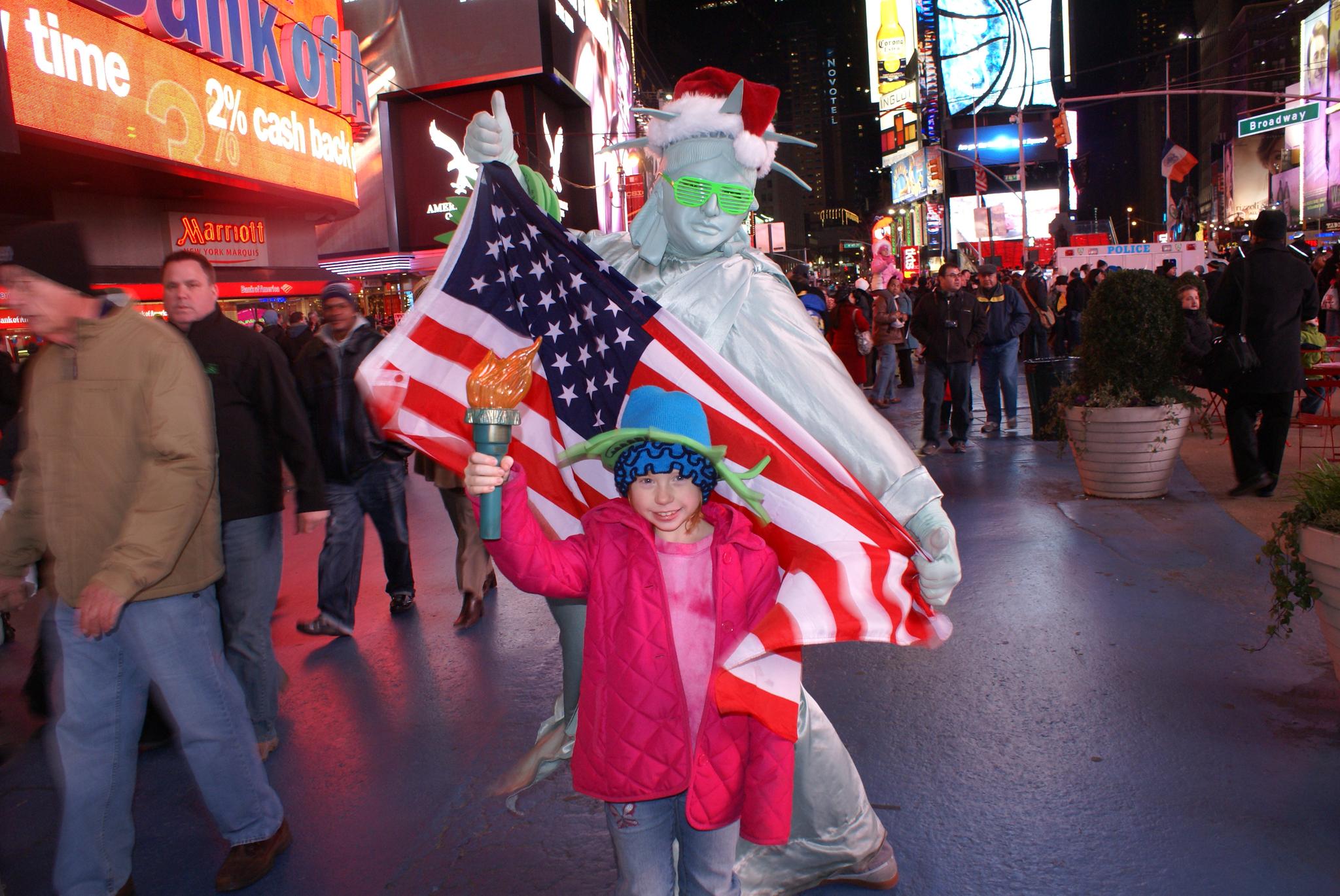 A family member smiling in NYC with a person painted in silver and holding an American flag