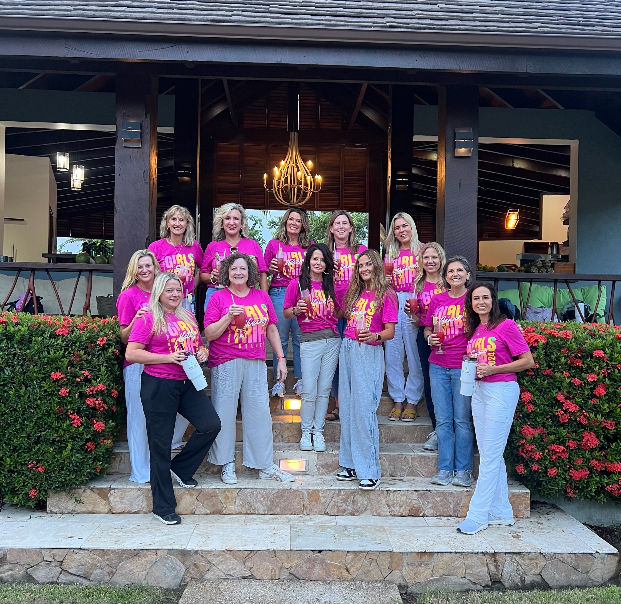 A group of ladies wearing pink shirts are smiling in front of the resort.